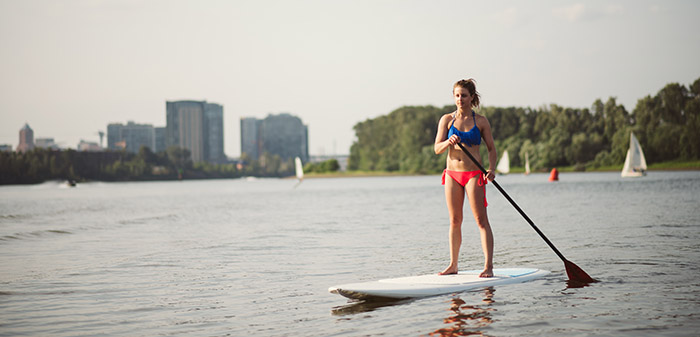 A paddle boarder on the lake with the city behind
